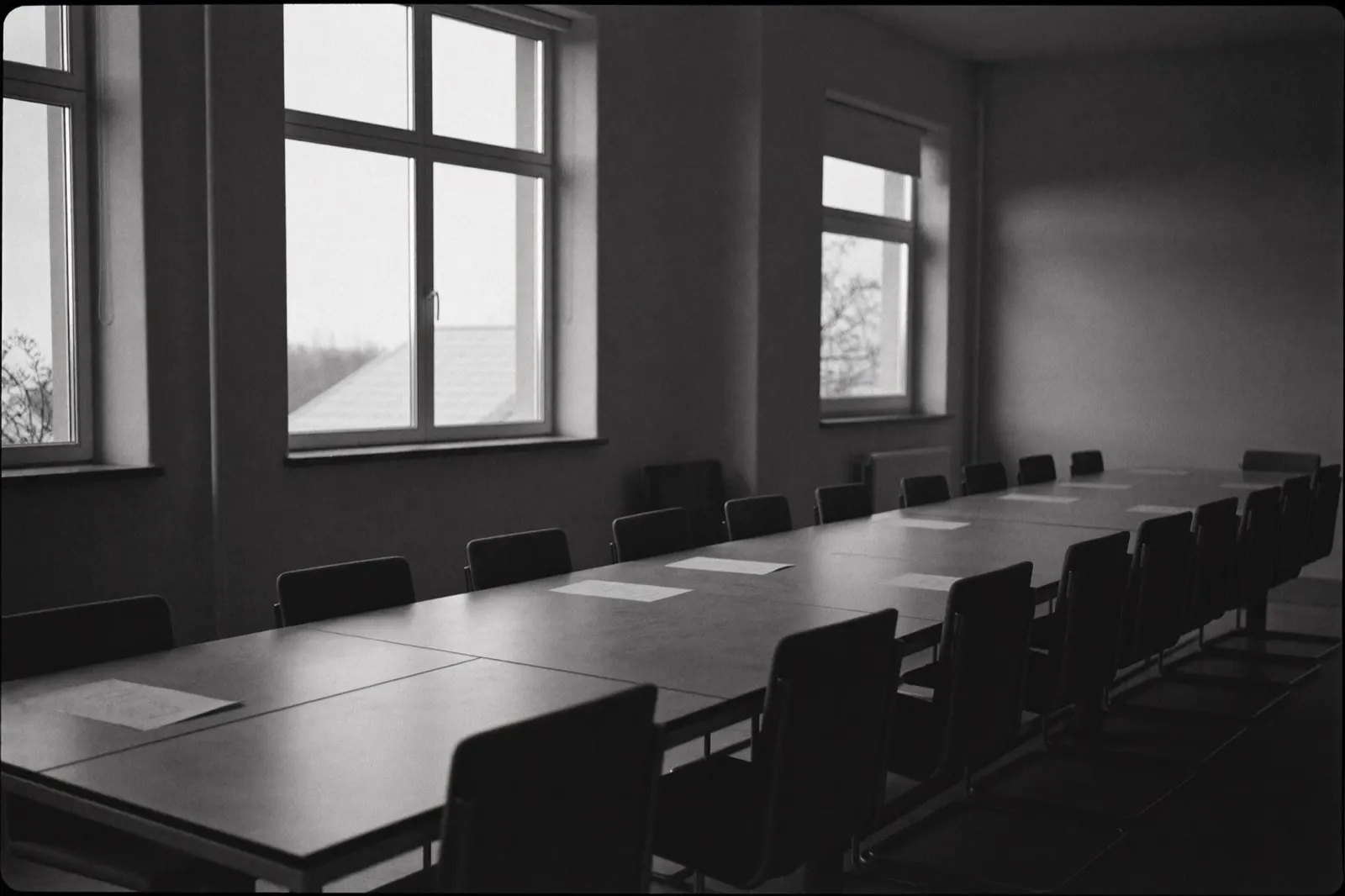 Empty boardroom table beside tall windows